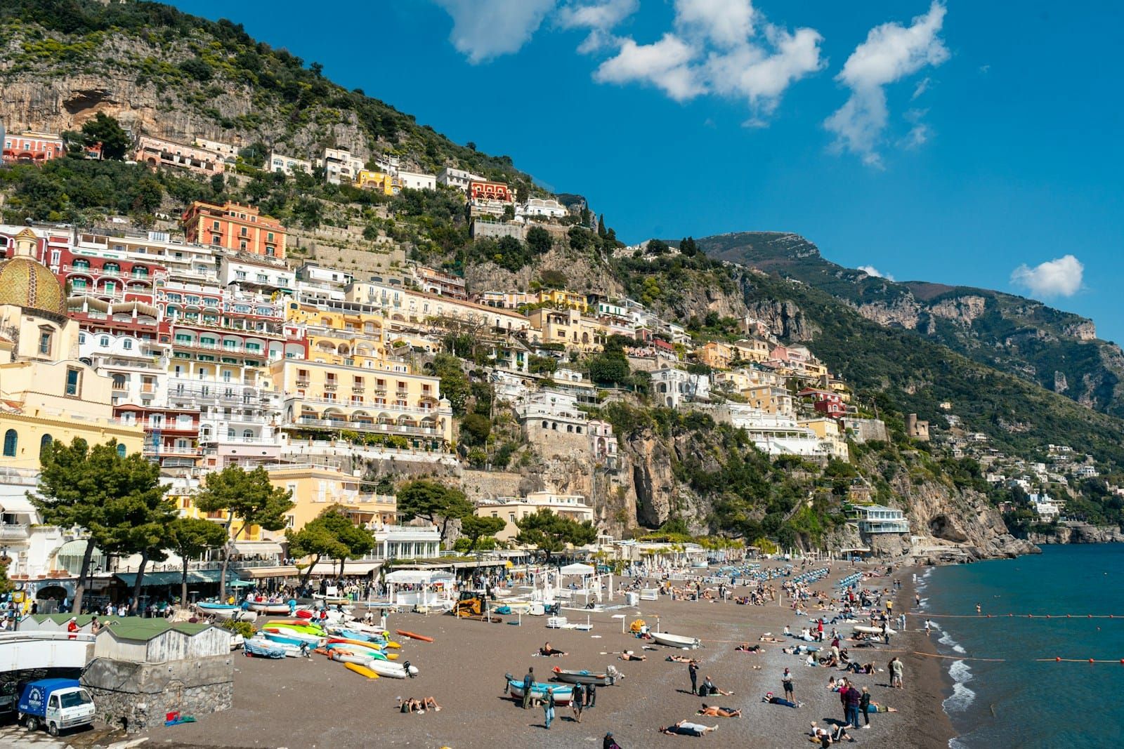 Positano on the Amalfi Coast, with houses stacked up a steep hillside above a busy pebble beach